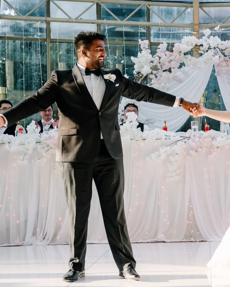 A groom throws his arms wide on the dance floor